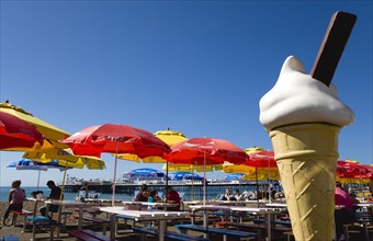 ENGLAND, East Sussex, Brighton, The Pier with people under sunshade umbrellas by tables on the