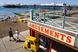 ENGLAND, East Sussex, Brighton, The Pier with people on the shingle pebble beach walking along the