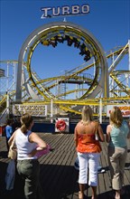 ENGLAND, East Sussex, Brighton, Women watching the Turbo rollercoaster amusement ride on Brighton