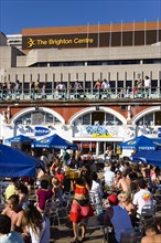 ENGLAND, East Sussex, Brighton, People sitting under sun shade umbrellas at tables on the promenade