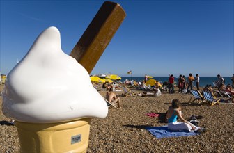 ENGLAND, East Sussex, Brighton, People sunbathing on the pebble shingle beach with a giant