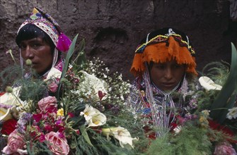 PERU Cusco Pisac Young couple in traditional dress behind flower display during village festival