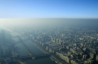 France, Ile de France, Paris, Aerial view over city and river through thick smog.