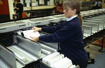 England, East Sussex, Brighton, Female Postal worker collecting sorted mail at the end of the OCR