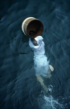 Japan, Honshu, Toba, Traditional female pearl diver swimming in the water with wooden barrel for