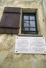 France, Ile de France, Coupvray, Marble commemorative plaque under a shuttered window on the wall