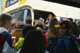 England, East Sussex, Brighton, Young teenage people boarding a crowded bus at a bus stop in the