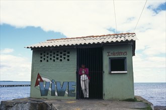 CUBA, West Coast, Vinales,Woman standing in doorway of drinks store building with Vive painted on