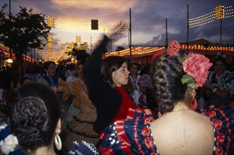 Spain, Andalucia, Seville, Female flamenco dancers dancing at sunset in traditional costume during