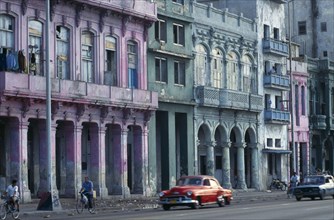 CUBA, Havana, Malecon street scene with crumbling exterior facades of buildings painted pink, blue