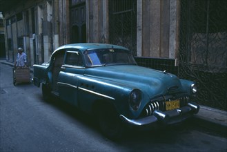 CUBA, Havana, Old blue American car with missing back door parked in street.