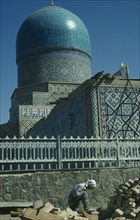 UZBEKISTAN, Samarkand, Bibi-Khanym Mosque exterior with construction worker in the foreground.