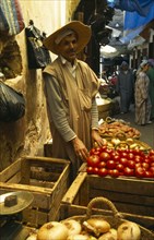 MOROCCO, Fez, Male stallholder behind crates of produce at the fruit market in the souk, pair of