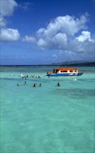 West Indies, Caribbean, Tobago, Tourists swimming in the shallow water beside a glass bottomed boat