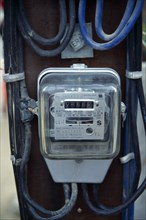 Thailand, Bangkok, Electricity supply meter showing reading and power cables running to it.