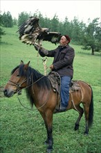 China, Xinjiang Province, Altay Mountains, Kazakh falconer on horseback with eagle used for hunting
