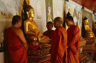 Thailand, Chiang Mai, Buddhist monks at Wat Doi Suthep praying on behalf of a family beside seated
