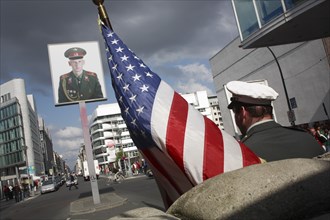 Germany, Berlin, American soldier & flag at Checkpoint Charlie on Friedrichstrasse.