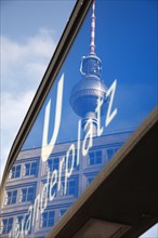 Germany, Berlin, U Bahn sign for Alexanderplatz with Fernsehturm reflected in the glass.