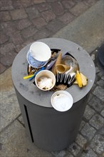 GERMANY, Saxony, Dresden, Street litter bin on sidewalk pavement full of rubbish.