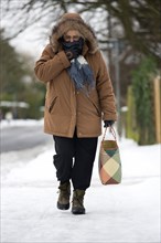 England, West Sussex, Chichester, Middled aged woman in warm clothing carrying shopping bag and