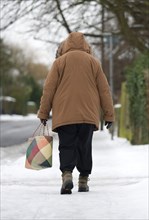 England, West Sussex, Chichester, Middles aged woman in warm clothing carrying shopping bag and