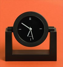 Time, Clocks, Analogue, Battery powered black analogue quartz table or desk clock against a red