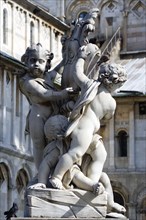 ITALY, Tuscany, Pisa, A statue of three Cherubs in front of the Duomo Cathedral in The Campo dei