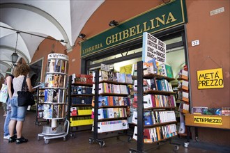 ITALY, Tuscany, Pisa, Two women looking at books ina display outside a bookshop underneath an