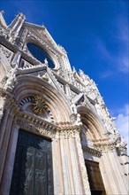 ITALY, Tuscany, Siena, The pink black and white marble facade of the Duomo cathedral church of
