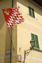ITALY, Tuscany, San Quirico D'Orcia, Red and white flag and crest of the Castello Quartieri or