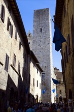 ITALY, Tuscany, San Gimignano, Via di Querececchio lined with flags and busy with tourists walking