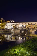 ITALY, Tuscany, Florence, Ponte Vecchio medieval bridge across River Arno illuminated at night with