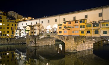 ITALY, Tuscany, Florence, Ponte Vecchio medieval bridge across River Arno illuminated at night with