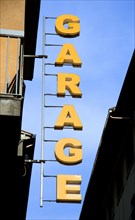 ITALY, Tuscany, Florence, Sign in yellow letters attached to building and hanging over street for a