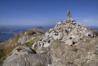 IRELAND, County Galway, Connemara, Diamond Hill, two hikers approach the stone pile at the summit