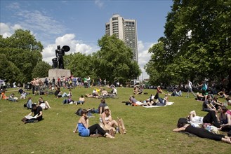 ENGLAND, London, Hyde Park, People sunbathing on a sunny day with blue sky and white clouds, at