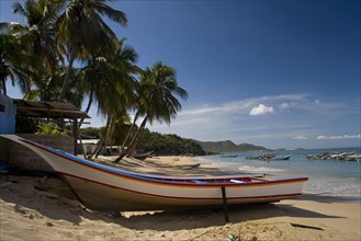 VENEZUELA, Margarita Island, Playa la Galera, Boat on the tropical beach just in front of a small
