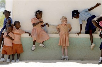 HAITI, Isla de la Laganave, School childrem in uniform playing, including an Albino girl.