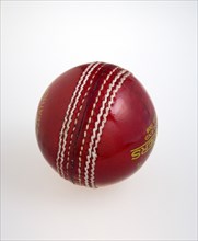 Sport, Ball Games, Cricket, Red hand stitched leather cricket ball on a white background.