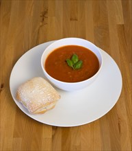 Food, Cooked, Soup, Bowl of tomato and basil soup on a plate with a rustic bread roll on a wooden