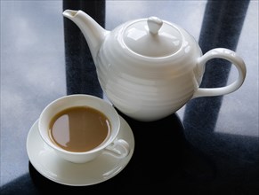 Drink, Hot, Tea, Cup of tea in a cup and saucer beside a teapot on a black granite kitchen worktop