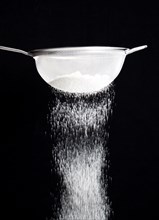 Food, Baking, Flour, White plain flour being siifted through a sieve against a black background.