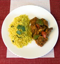 Food, Cooked, Curry, Indian chicken Jalfrezi curry with yellow pilau rice on a white plate.