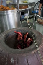Malaysia, Kuala Lumpur, Skewered Tandoori chicken while being baked inside a Tandoor Oven at the