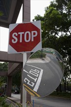 Singapore, stop traffic sign and a curved mirror reflecting the stop letters on the road surrounded