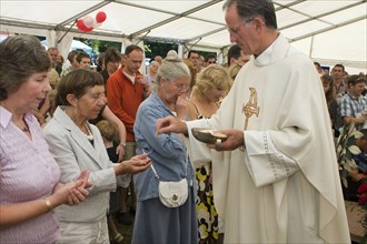 Religion, Christian, Catholic, Worshippers receiving holy communion in their hands from priest.