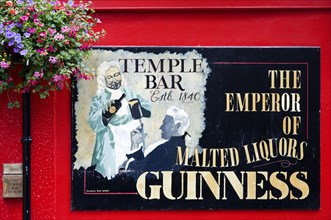 Ireland, County Dublin, Dublin City, Temple Bar pub sign on red wall promoting Guinness.