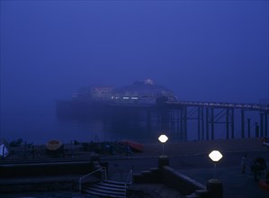 Brighton, East Sussex, England. The West Pier illuminated in evening light with mist on the sea