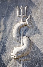 Athens, Attica, Greece. Close cropped view of stone carving of sea creature curved around trident.